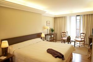 a bedroom with a large bed and a living room at Hôtel des Pyrénées in Saint-Jean-Pied-de-Port