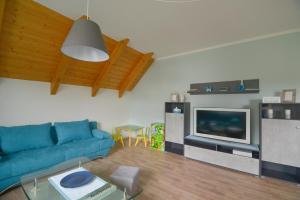 a living room with a blue couch and a tv at Ferienwohnung am großen Stein in Leutersdorf