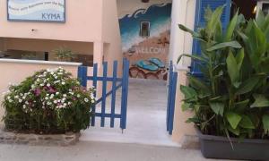 a blue gate in front of a building with flowers at Hotel Kyma in Skala Eresou