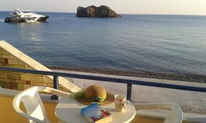 a table with a hat and a book on a balcony with the ocean at Hotel Kyma in Skala Eresou