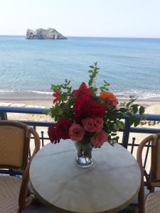 a vase of flowers on a table near the beach at Hotel Kyma in Skala Eresou