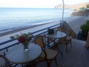 two tables and chairs with a view of the beach at Hotel Kyma in Skala Eresou