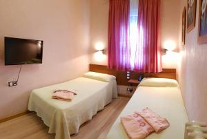 two beds in a hotel room with pink curtains at Hostal De La Torre Hostal Economico in Valladolid