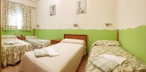 Habitación con 2 camas y paredes verdes en Hostal De La Torre Hostal Economico, en Valladolid