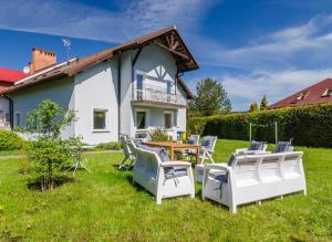 a yard with chairs and a table and a house at Szary Domek Apartamenty Ustka in Ustka