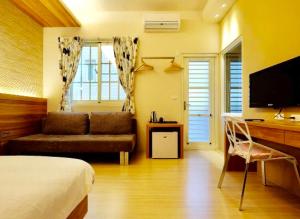 a bedroom with a bed and a desk with a television at Pretty B&B in Hualien City