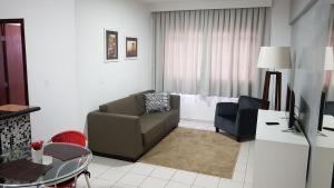 a living room with a couch and a tv at Lavras Apart Hotel in Lavras