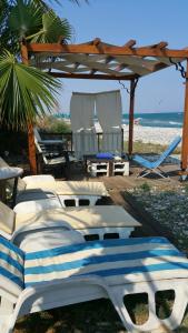 een groep bedden op een strand met een prieel bij Aquarian Beachfront Apartment in Larnaka