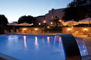a swimming pool with a waterfall and umbrellas at night at Kyriad Nantes Sud - Bouaye Aéroport in Bouaye