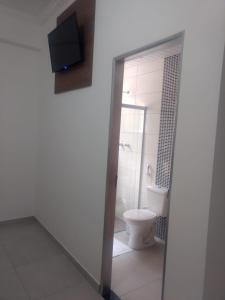 a bathroom with a toilet and a tv on the wall at Hotel farol de Minas in Alpinópolis +26 photos