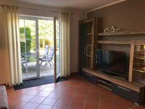 a living room with a tv and a sliding glass door at Ferienwohnung Dora in Medebach