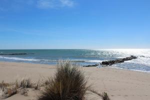 a sandy beach with rocks in the ocean at Studio 237 Port Camargue, Piscine, Climatisation, 2 personnes in Le Grau-du-Roi