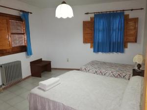1 dormitorio con 2 camas y cortinas azules en Apartamentos Cerro Negro, en Capileira