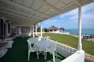 eine Veranda mit einem Tisch, Stühlen und Meerblick in der Unterkunft Beyond Sunset Resort & Villas in Treasure Beach