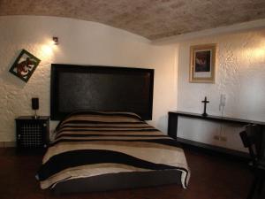 a bedroom with a bed with a cross on the wall at Casa Blanca San Miguel in San Miguel de Allende