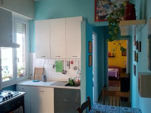 a kitchen with white cabinets and a blue wall at 4321 B&B Stazione Trastevere in Rome