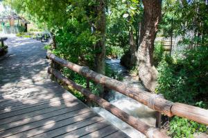 een houten hek naast een rivier met bomen bij El Rollo Camping in Tlaquiltenango