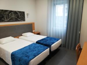 una camera d'albergo con due letti e una finestra di Whalesbay Hotel Apartamentos a Capelas