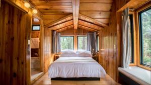 ein Schlafzimmer mit einem Bett in einem Holzhaus in der Unterkunft Cabaña en el corazón de Avandaro in Avándaro