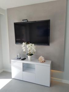 a white entertainment center with a flat screen tv on a wall at Gold Platinium apartament z widokiem na morze in Rewal