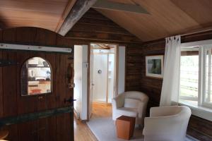 Zimmer mit Holzwänden, weißen Stühlen und einer Tür in der Unterkunft Gallery B&B in Ganges