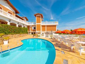 a swimming pool in front of a building with chairs and umbrellas at Hotel Guanumbis in Ilhabela