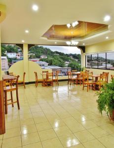 un restaurante con mesas y sillas de madera y una gran ventana en Hotel Palmeras de Elim, en Matagalpa