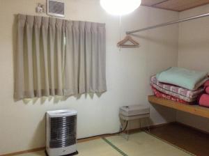 a room with a room with a heater and a window at Minshuku Akiba in Furano