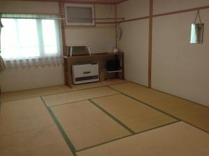 an empty room with a room with a table at Minshuku Akiba in Furano