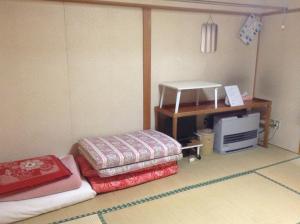 a small room with two beds and a desk at Furano Minshuku Akiba in Furano
