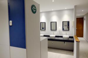 a bathroom with four sinks with mirrors on a counter at izZzleep Aeropuerto Terminal 2 in Mexico City