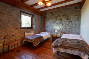 2 łóżka w pokoju z kamienną ścianą w obiekcie URAIN Suites - Apartments at Flysch-Coast w mieście Zumaia