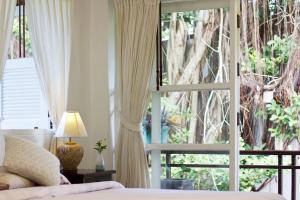 a bedroom with a bed and a large window at Banyan House Samui bed and breakfast (Adult Only) in Chaweng