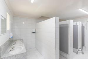 a white bathroom with two sinks and a mirror at Mandurah Caravan and Tourist Park in Mandurah