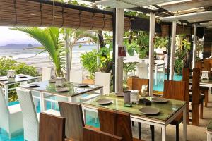 ein Restaurant mit einem Tisch, Stühlen und Meerblick in der Unterkunft At Seacondo-Studio-B26 in Klong Muang Beach