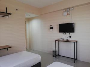 ein Schlafzimmer mit Bett und Flachbildfernseher in der Unterkunft Eon Centennial Express Hotel in Iloilo City