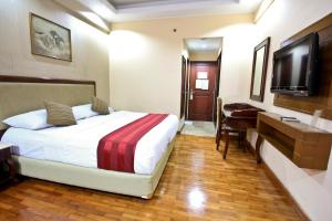 a bedroom with a bed and a desk and a television at Grand Menteng Hotel in Jakarta