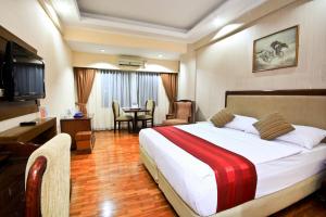 a hotel room with a large bed and a table at Grand Menteng Hotel in Jakarta