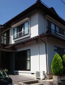 Cette maison blanche dispose de fenêtres et d'un balcon. dans l'établissement Guest house Minna no Ie, à Achi