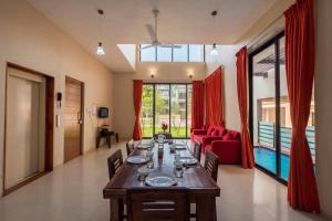 a dining room with a long table and a red couch at StayVista's Greenwoods Villa 9 - City-Center Villa with Private Pool, Terrace, Lift & Ping-Pong Table in Lonavala