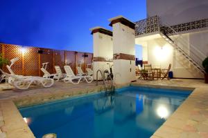 a swimming pool with chairs and a table at The Mayflower Hotel in Beirut
