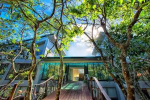 una casa circondata da alberi con un vialetto in legno di Toptai Homestay a Kenting