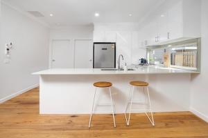 a white kitchen with two bar stools and a counter at Staughton Sounds in Capel Sound