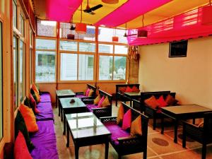 Zimmer mit Tischen, Stühlen und rosafarbener Beleuchtung in der Unterkunft La Casa in Haridwar