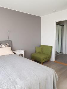 - une chambre avec un lit et une chaise verte dans l'établissement 57 Kauppakatu, à Varkaus