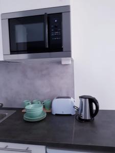 eine Küche mit Mikrowelle, Toaster und Geschirr in der Unterkunft 57 Kauppakatu in Varkaus