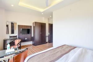Un dormitorio con una cama y un televisor en una habitación. en Hotel Kaithli Hills Shimla, en Shimla