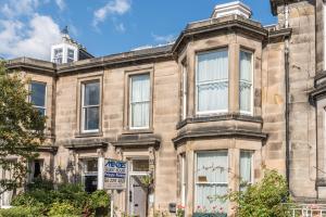 an old stone house with a sign in front of it at Menzies Guest House in Edinburgh