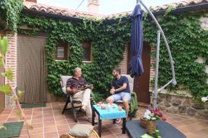 zwei Männer auf einer Terrasse mit Sonnenschirm in der Unterkunft La Casita de Adanero in Adanero