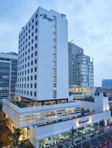 a tall white building with a sign on the side of it at de Braga, ARTOTEL Curated in Bandung